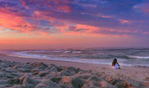 stunning-sunset-lady-sitting-on-the-shore-of-ocean